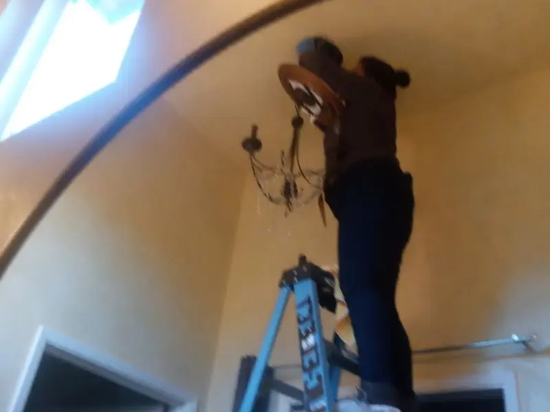 Electrician installing a chandelier in a Weisenberg residence